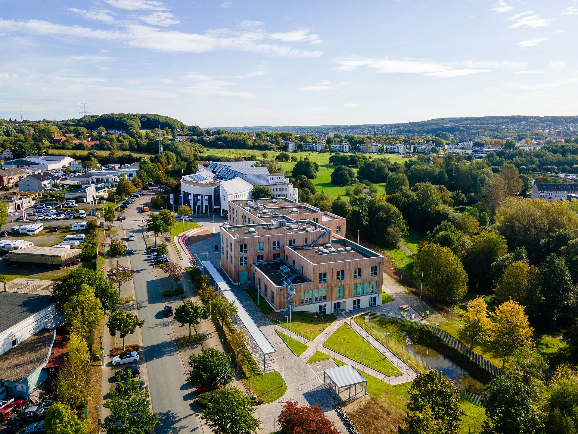 Luftaufnahme von zwei Universitätsgebäuden, die mitten im Grünen liegen.
