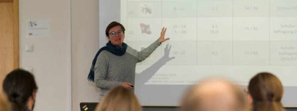 Eine Professorin steht vor Studierenden und hält eine Vorlesung.