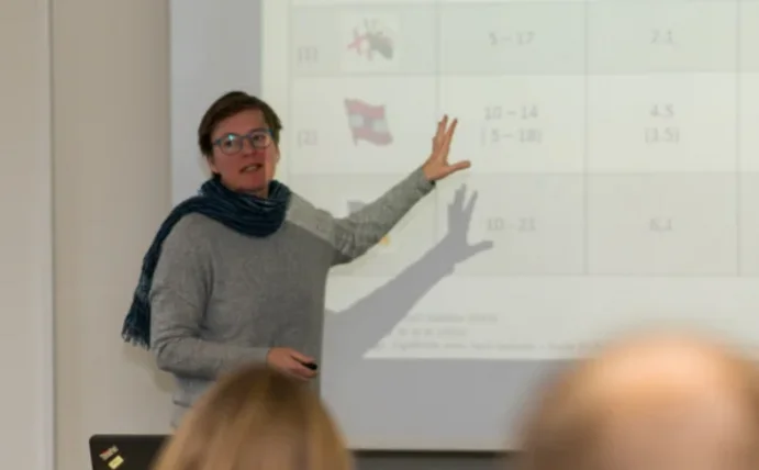 Eine Professorin steht vor Studierenden und hält eine Vorlesung.