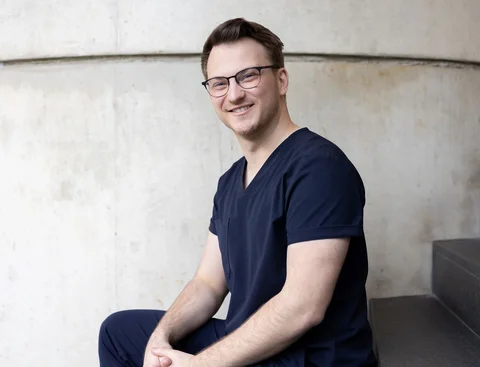 Bewirb dich für den Studiengang Zahn-, Mund- und Kieferheilkunde (StEx) an der UW/H. (Foto: UW/H | Michael Schwettmann) Ein junger Mann sitzt auf einer Treppe vor einer Betonwand.