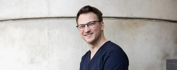 Bewirb dich für den Studiengang Zahn-, Mund- und Kieferheilkunde (StEx) an der UW/H. (Foto: UW/H | Michael Schwettmann) Ein junger Mann sitzt auf einer Treppe vor einer Betonwand.
