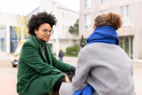 Auf dem Campus der UW/H (Foto: UW/H | Michael Schwettmann) Zwei Studentinnen sitzen auf dem Campus der UW/H und sprechen miteinander.