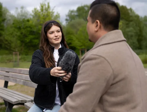Eine Frau interviewt einen Mann mit einem Mikrofon.