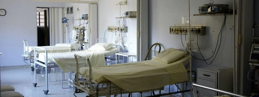 Three empty hospital beds in a hospital room.