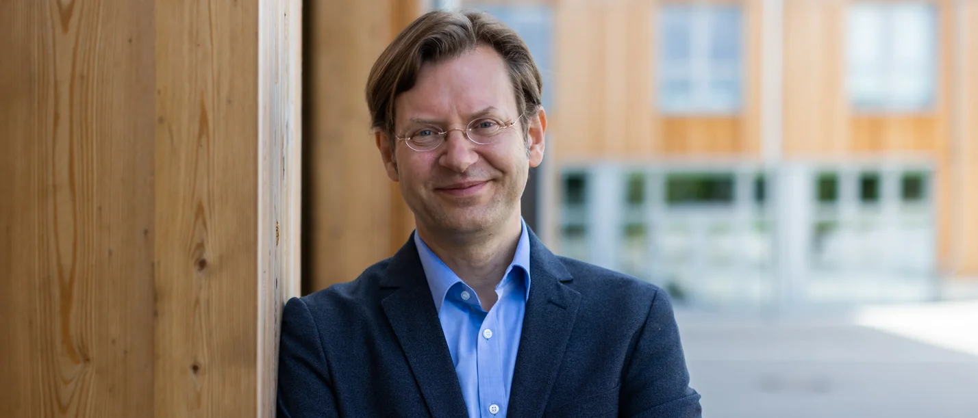 Portrait von Prof. Dr. Heiko Kleve (Foto: UW/H) Portrait eines Mannes vor einer Holzwand