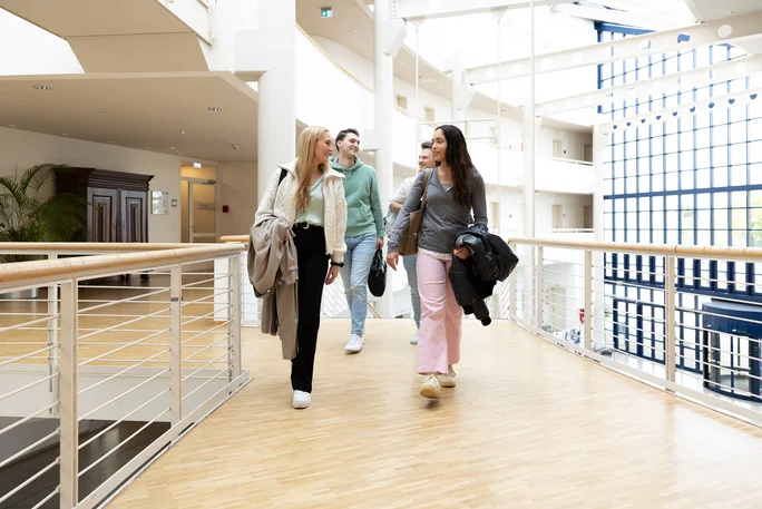 Studierende laufen zum Seminar im weiß-blauen Gebäude der UW/H.
