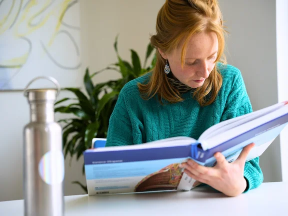 Elsa Heinsius sitzt an einem Tisch und liest in einem Medizin-Fachbuch.