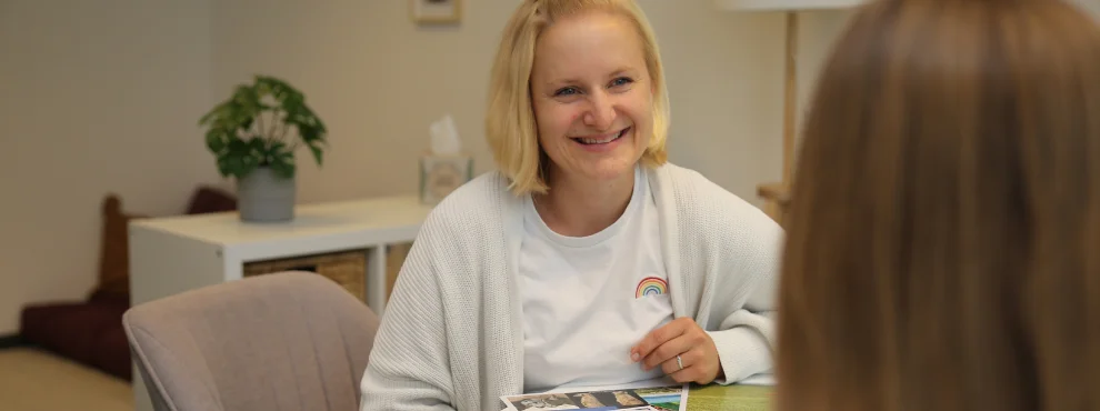 Eine Frau spricht mit einem Mädchen, das mit dem Rücken zur Kamera sitzt.