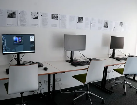 Monitore und Tastaturen auf Tischen an einer Wand