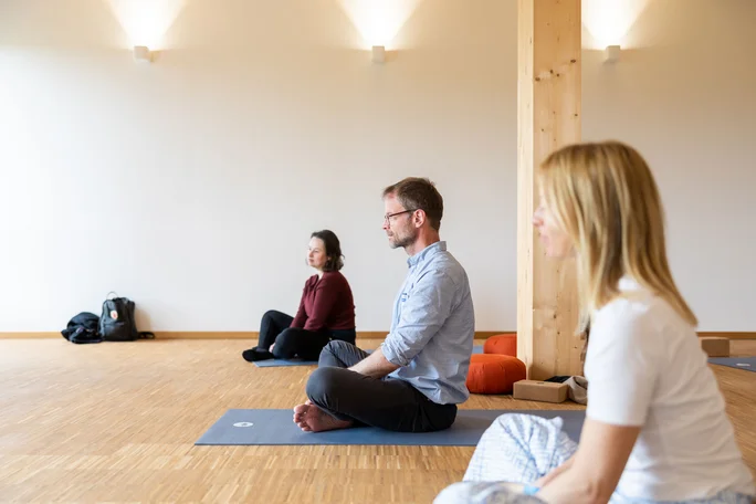 Mind-Body Balance Workshop (Photo: UW/H | Michael Schwettmann) Three people are sitting in the yoga pose on exercise mats.