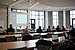 Ein Dozent hält einen Vortrag vor einer Seminargruppe. Hinter ihm wird eine Präsentation an die Wand projiziert.