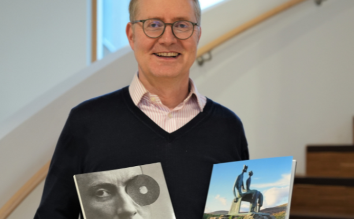 Portrait eines Mannes. Er hält zwei Kunstbücher in den Händen.