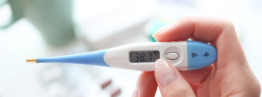 Eine Hand hält ein Fieberthermometer.