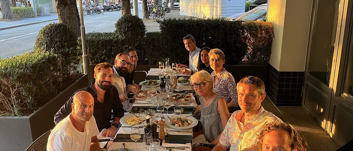 Eine Gruppe Menschen sitzt zum Essen auf einer Restaurantterrasse.