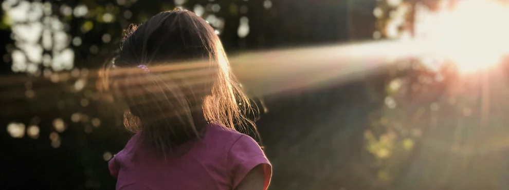 Ein Mädchen schaut in die Sonne.