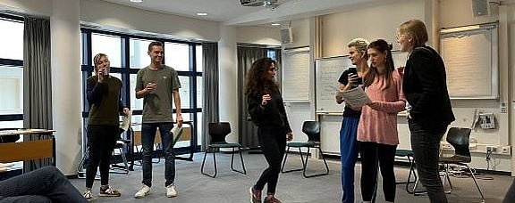 Studierende stehen diskutierend in einem Seminarraum