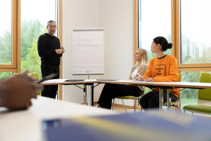 Seminar on the PPÖ (BA) degree programme at the UW/H (Photo: UW/H | Michael Schwettmann) A professor and two students are sitting in a seminar on the PPÖ (BA) degree programme.