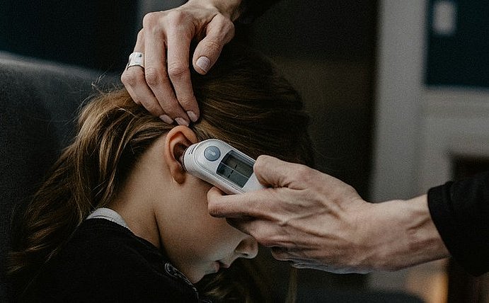 Taking a child's temperature correctly Child with clinical thermometer in ear
