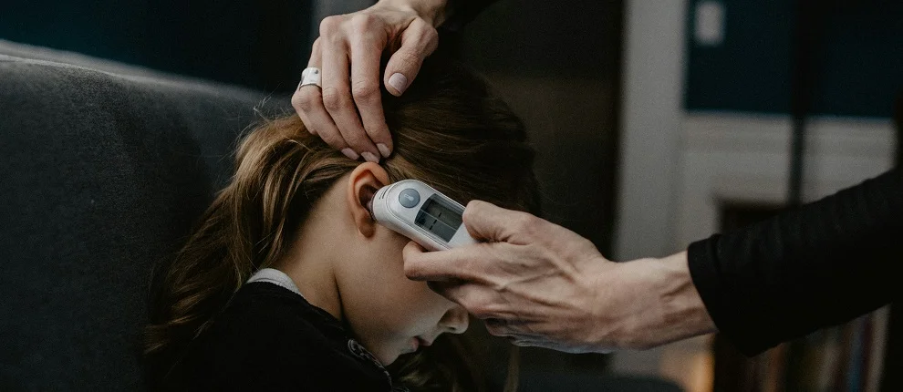 Child with clinical thermometer in ear