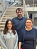 Drei Personen stehen auf einer Treppe und lächeln in die Kamera.