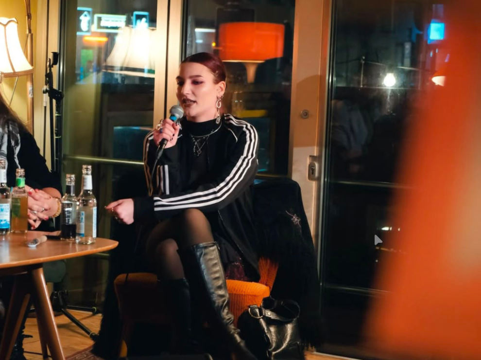 Ia Estella Pedroli was involved in activism from an early age and championed political education, amongst other things, at panel discussions. (Photo: Private) Ia Estella is sitting on a chair on a stage and speaking into a microphone.
