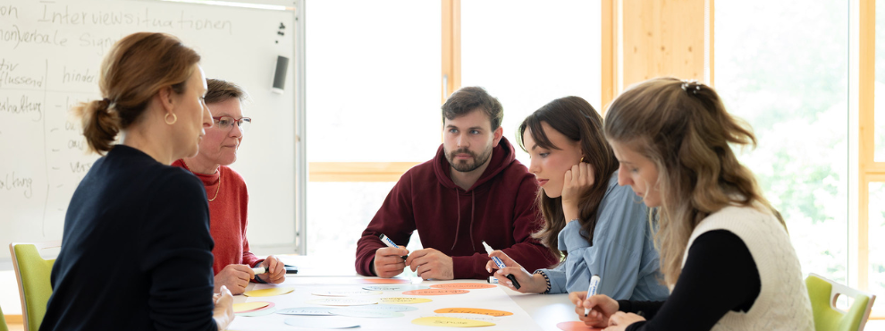 Professorin und Studierende sitzen an einem Tisch zum Dialog