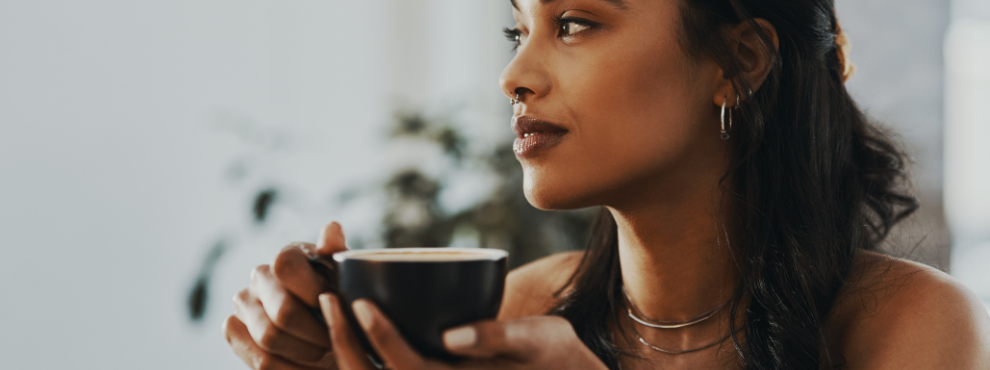 Eine Frau schaut in die Ferne und trinkt Tee.