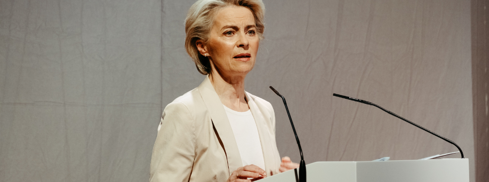 Eine Frau steht an einem Rednerpult und spricht in ein Mikrofon.