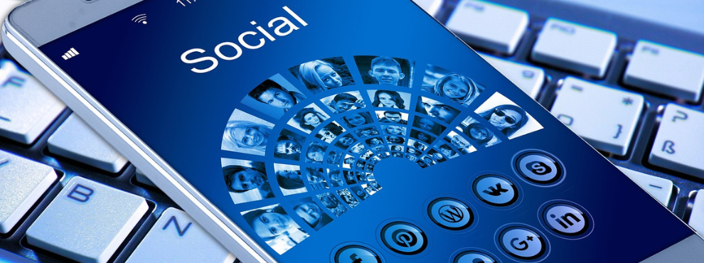 Die Daten aus Online-Selbsthilfegruppen haben das Potenzial, patient:innenzentrierte medizinische Innovationen zu fördern. (Foto: pixabay | geralt) Auf dem Bildschirm eines Smartphones steht "Social", darunter sind Porträts von Menschen in einem Halbkreis abgebildet, ebenso wie Icons von Social-Media-Plattformen.