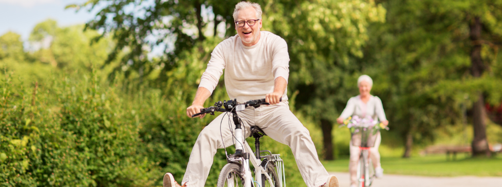 Trotz körperlicher Beschwerden und chronischer Krankheiten sind ältere Menschen in der Regel glücklicher und zufriedener als junge Erwachsene. (Foto: Canva) Ein Mann fährt auf einem Fahrrad und streckt die Beine aus.