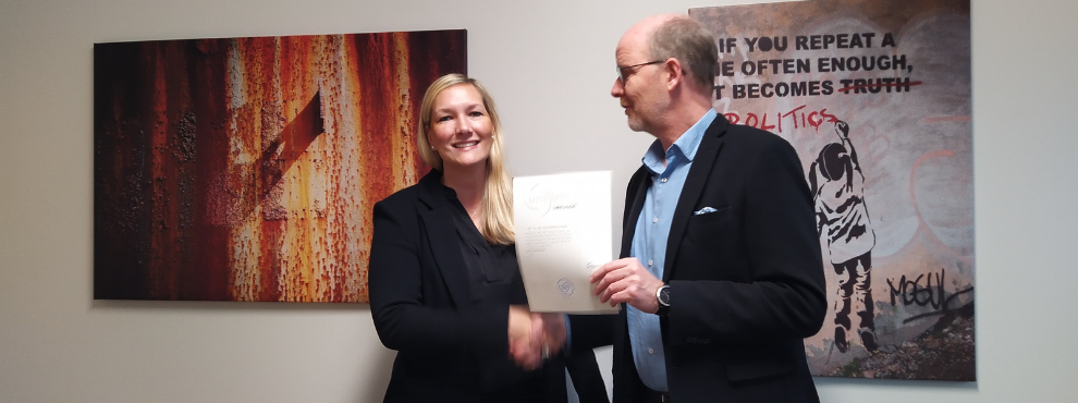 A man hands a woman a certificate and shakes her hand.