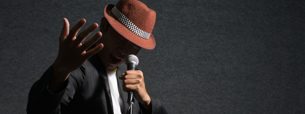 Man sieht einen Musiker, der ein Mikrofon in der Hand hält und singt.