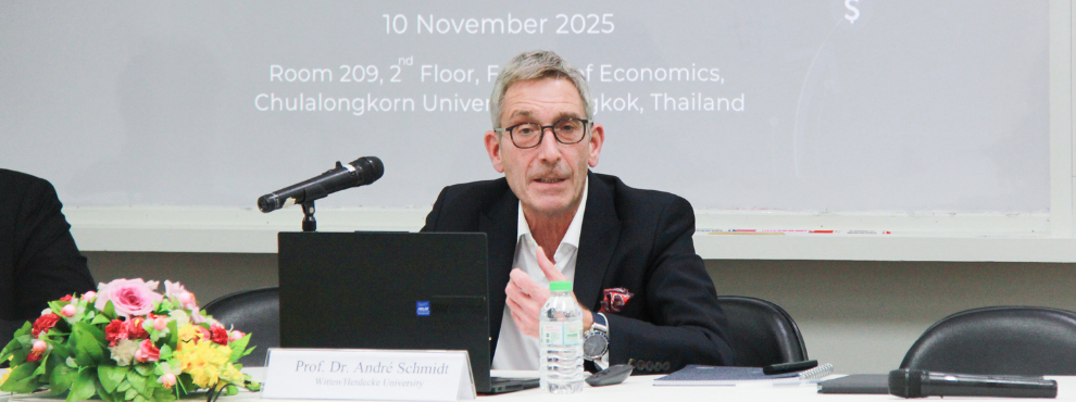 Prof Dr André Schmidt sits at a table in front of a microphone.