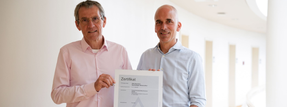 UW/H is the first university in Germany to be certified according to the ZNU standard. (Photo: UW/H) Two people hold a certificate up to the camera.