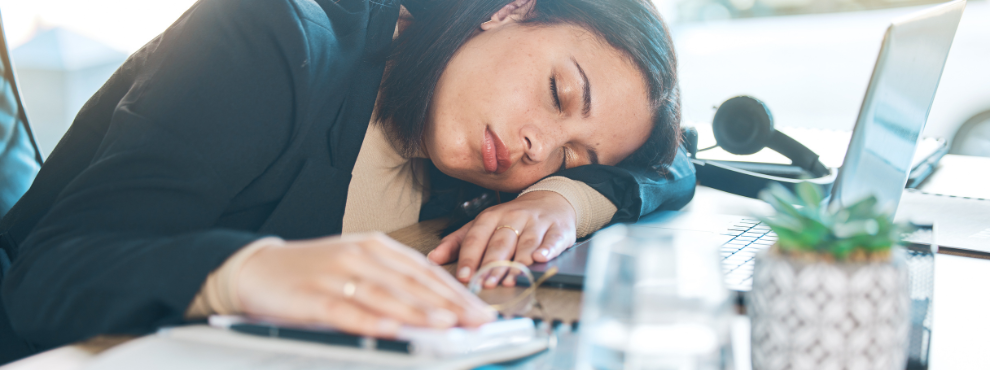 Eine neue Leitlinie zu Narkolepsie bietet Handlungsempfehlungen für Mediziner:innen und bessere Therapiemöglichkeiten für Betroffene (Foto: Canva). Das Foto zeigt eine schlafende Frau, die ihren Kopf vor dem Notebook auf den Schreibtisch abgelegt hat.