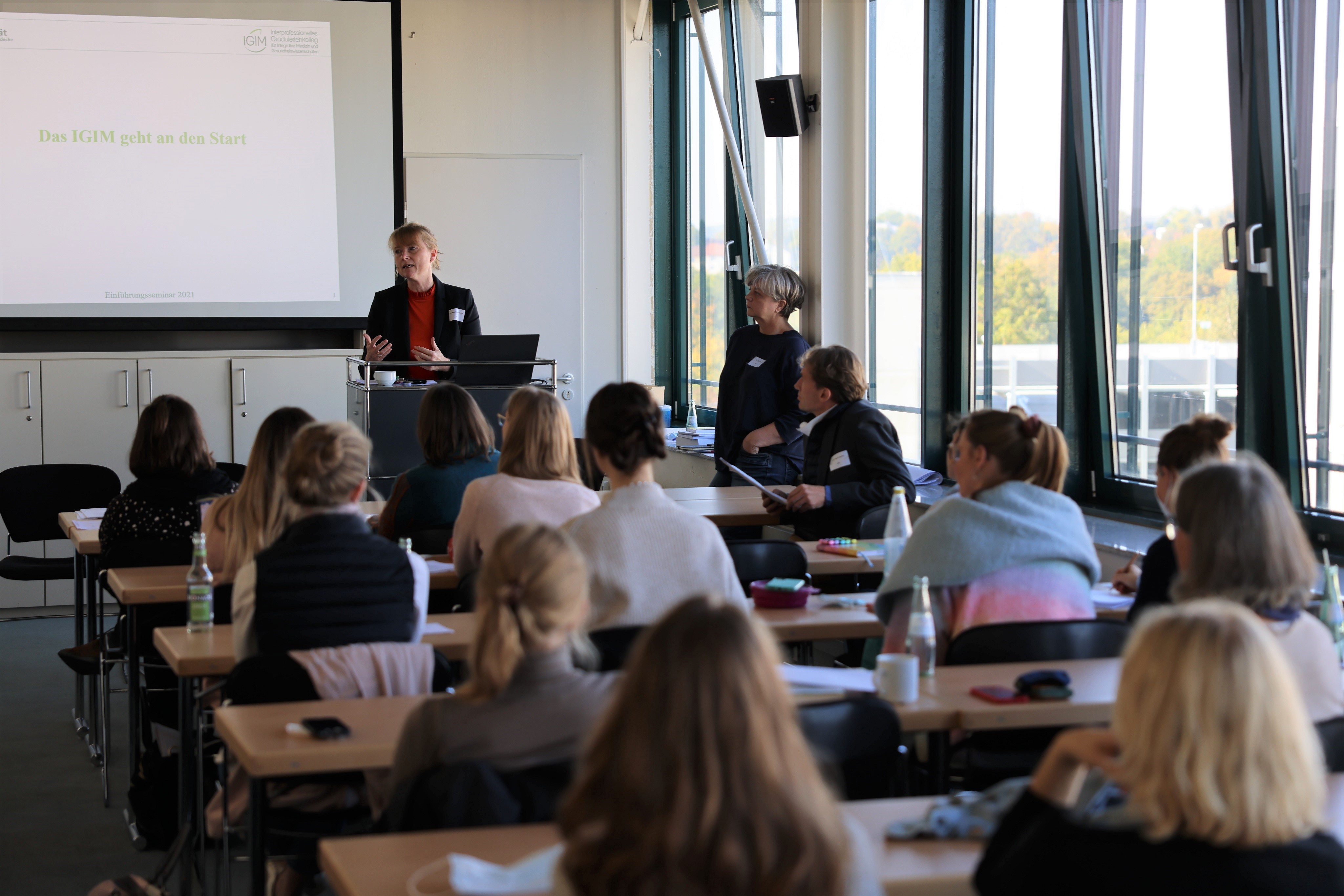 IGIM Einführungsseminar an der UW/H (Foto: David Roeder) Promovierende sitzen in einem Seminarraum und hören der Dozentin zu, die vorne steht.